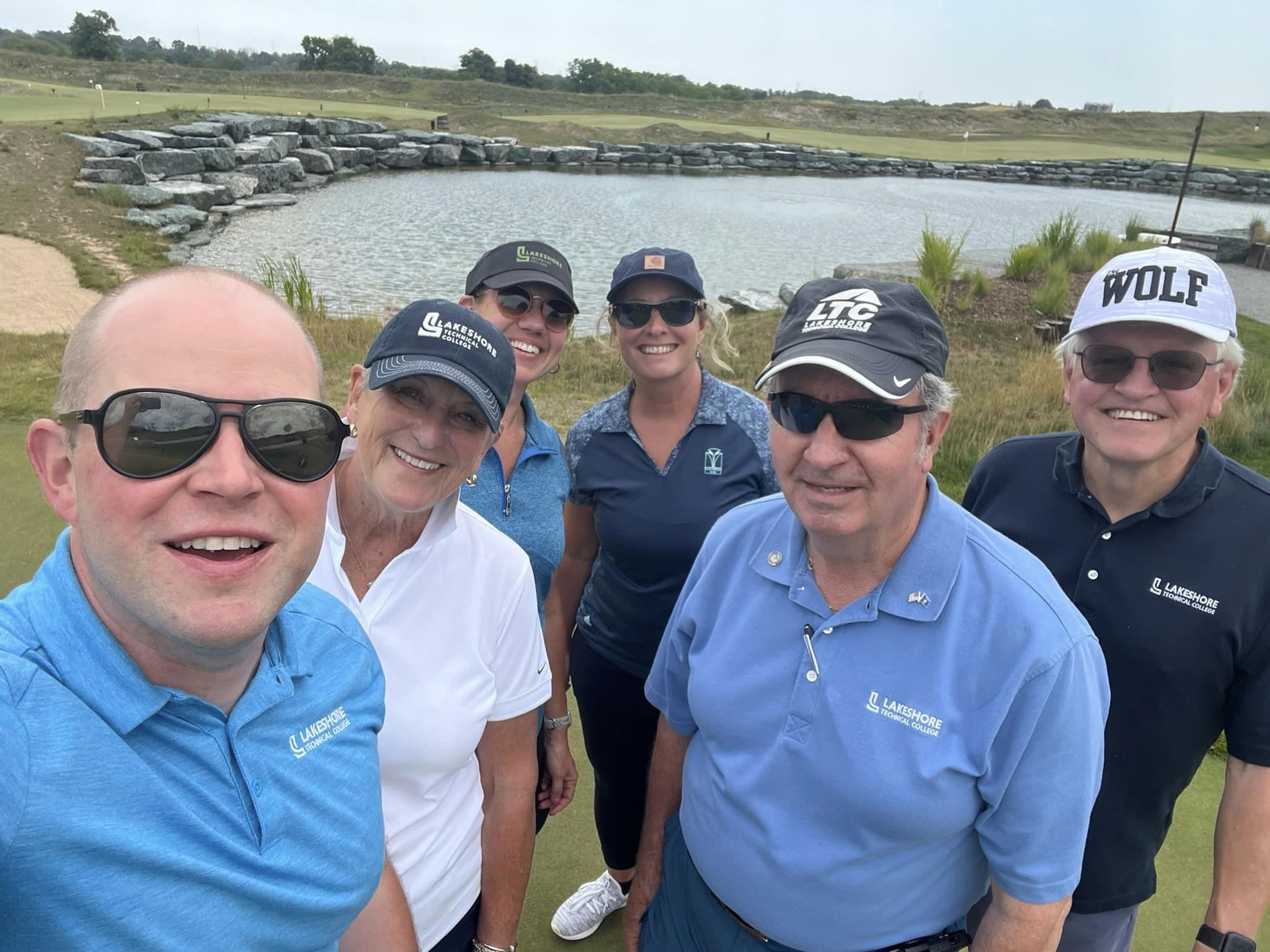 Participants of LTC Foundation Golf Event standing on a golf green by a lake