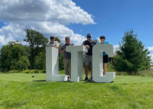 Participants of LTC Foundation Golf Event standing on a golf green by a lake