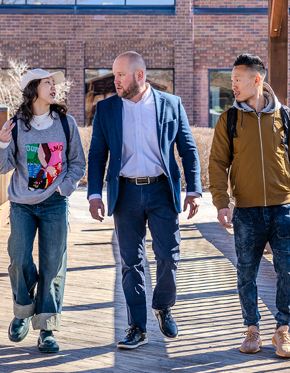 Three individuals walking down a bridge