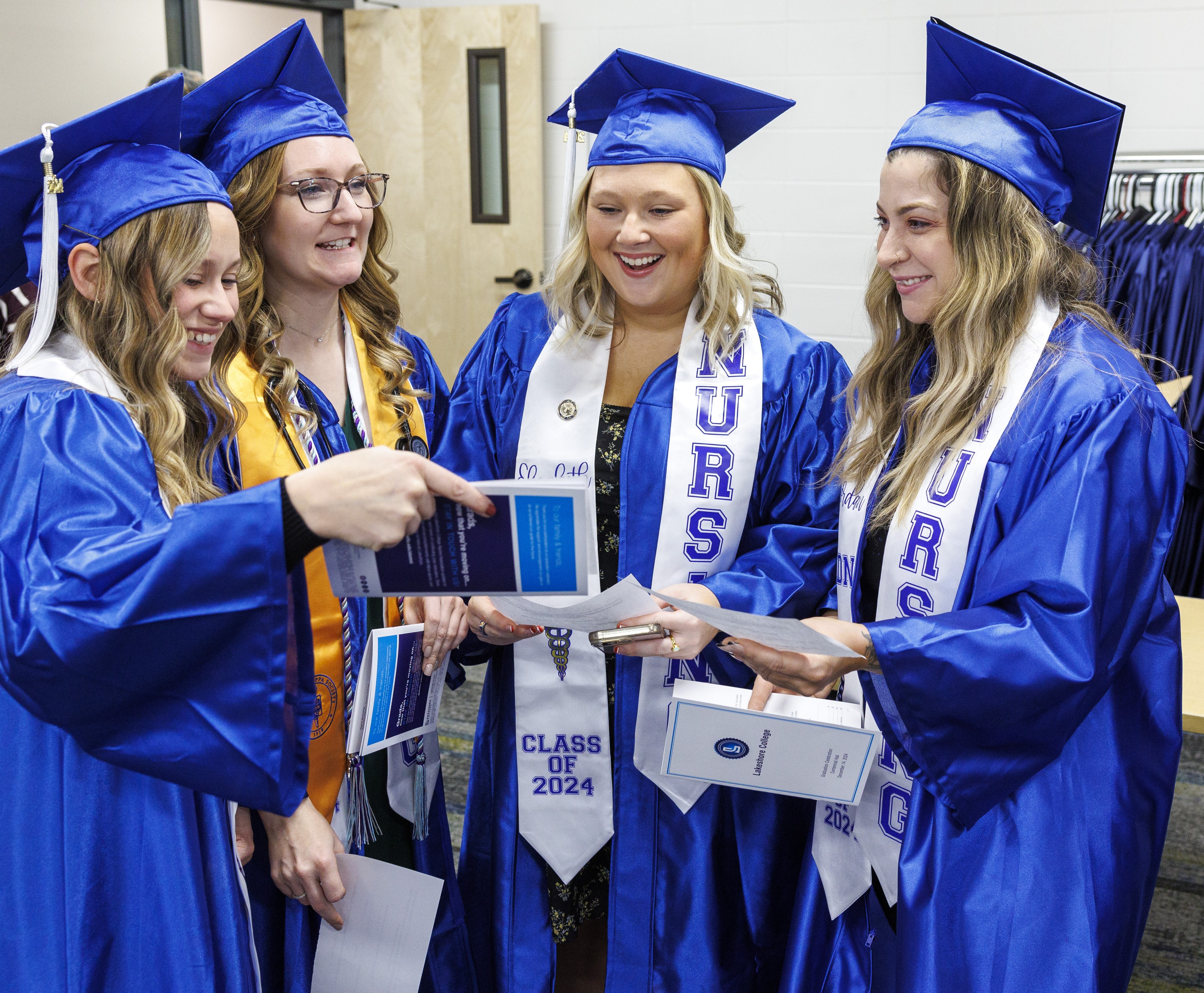 Four Lakeshore College graduates celebrating in their caps and gowns.
