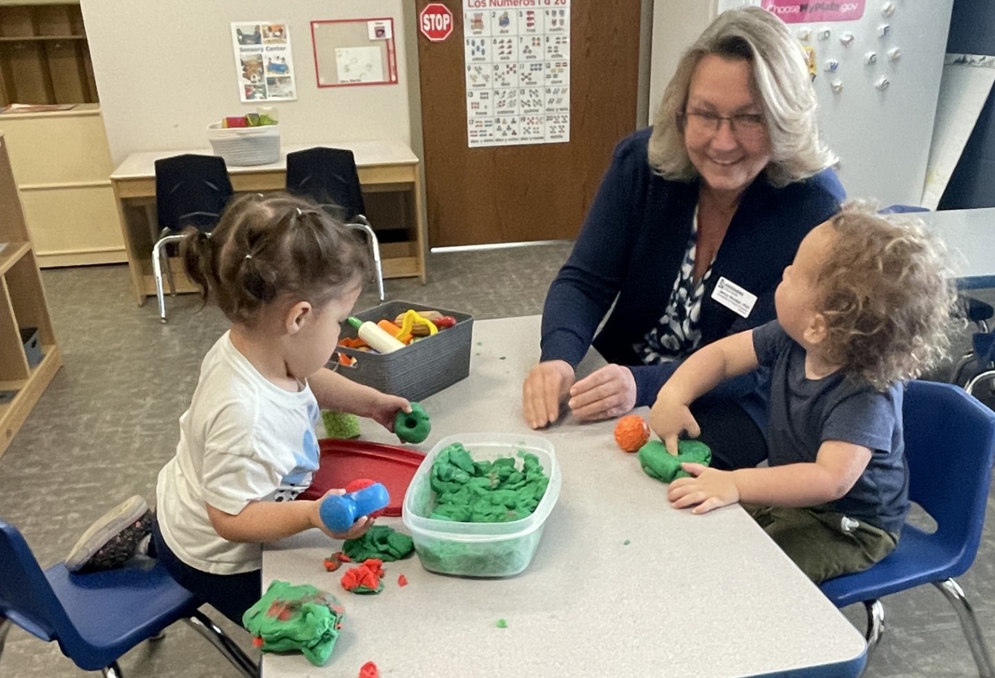Two young children play at a table with an instructor.