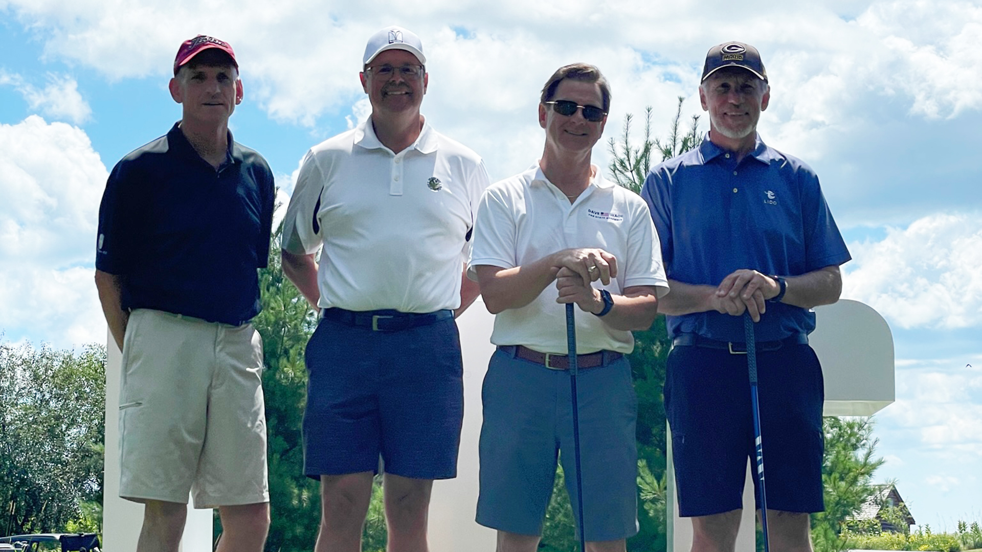 Participants of LTC Foundation Golf Event standing on a golf green by a lake