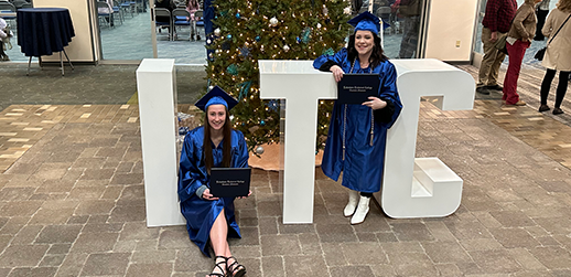 Two graduating students by large letters which spell LTC